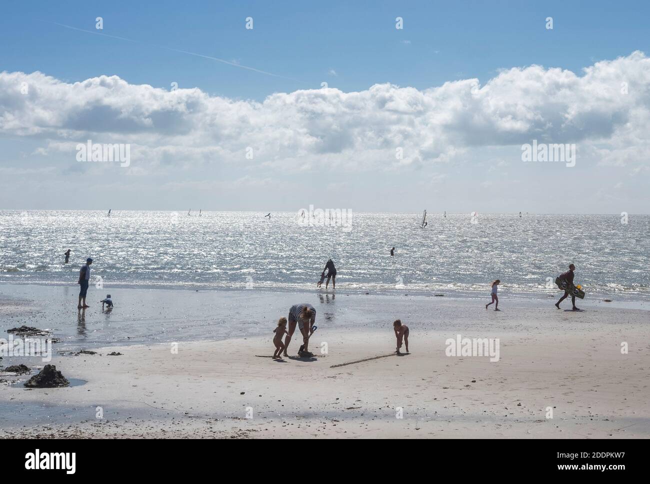 Gente de diferentes edades disfrutando de una tarde soleada en una playa de arena y en el mar en Hayling Island, Hampshire, Inglaterra, Reino Unido Foto de stock