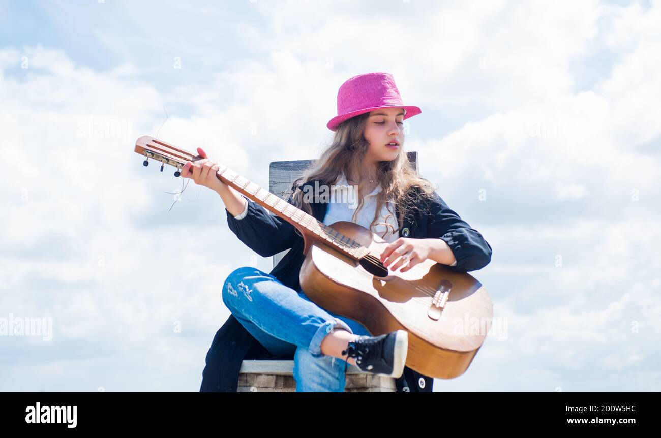 Belleza de estilo funky. Música y voz. Tocar el instrumento de guitarra.  Niño con guitarra acústica. Felicidad infantil. Chica adolescente muy joven  con ropa informal. Moda infantil. Cantante alegre Fotografía de stock -