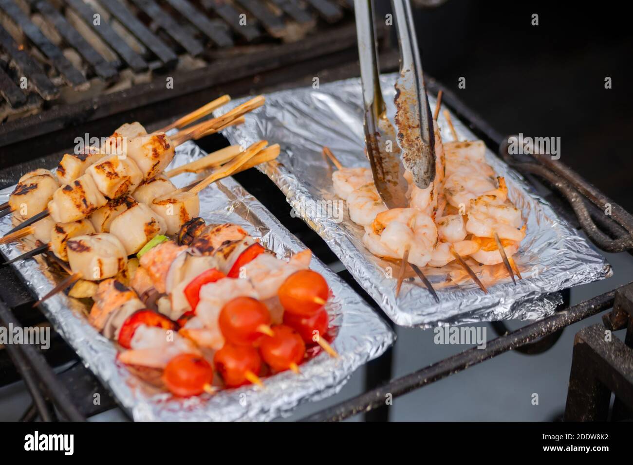 Vieiras y camarones cocidos, brochetas de gambas, tomate cherry sobre papel  de aluminio - comida callejera Fotografía de stock - Alamy