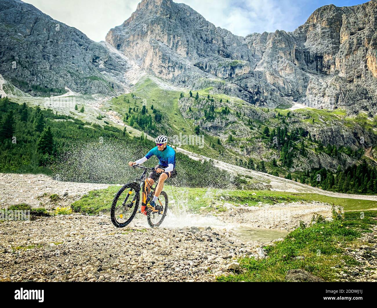 Hombre haciendo ciclismo de montaña en una ruta de montaña - Deporte El hombre que monta en bicicleta de montaña pasa por un poco profundo arroyo que pasa por la naturaleza tranquila Foto de stock