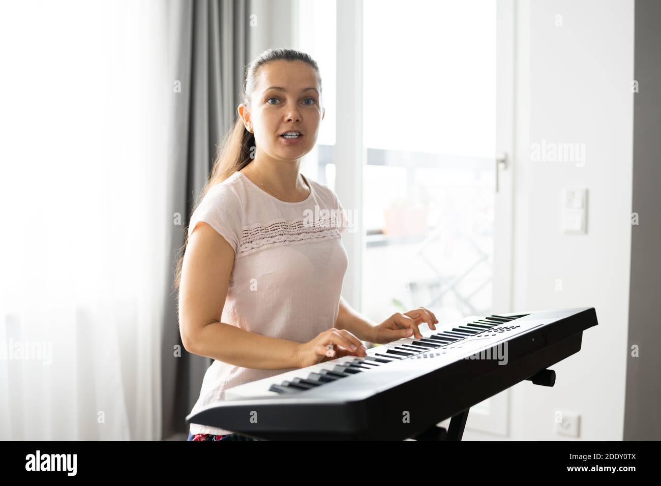 Mujer tocando el instrumento de piano de teclado de música en casa Foto de stock