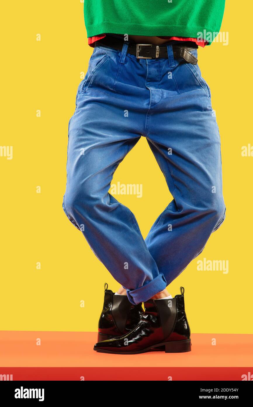 Las piernas de un joven hombre de moda en pantalones vaqueros azules y botas  negras en el piso rojo Fotografía de stock - Alamy