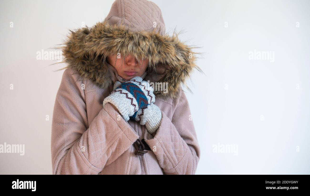 Mujer congelada vestida con abrigo cálido con capucha sobre su cabeza y  guantes de invierno cálidos. Espacio negativo o espacio de copia para texto  Fotografía de stock - Alamy