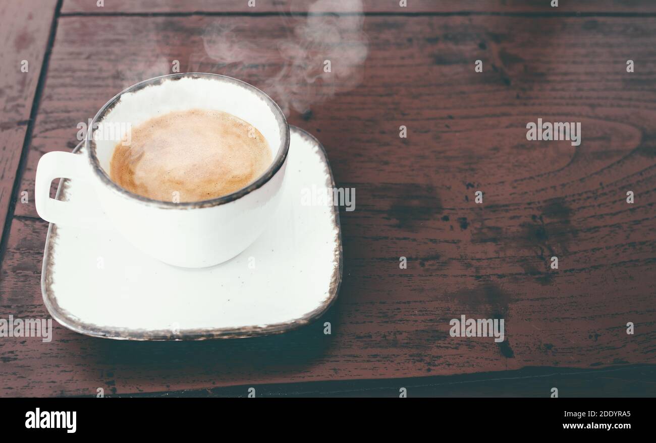 vista de primer plano de una taza de café expreso italiano caliente al vapor mesa de madera rústica roja Foto de stock