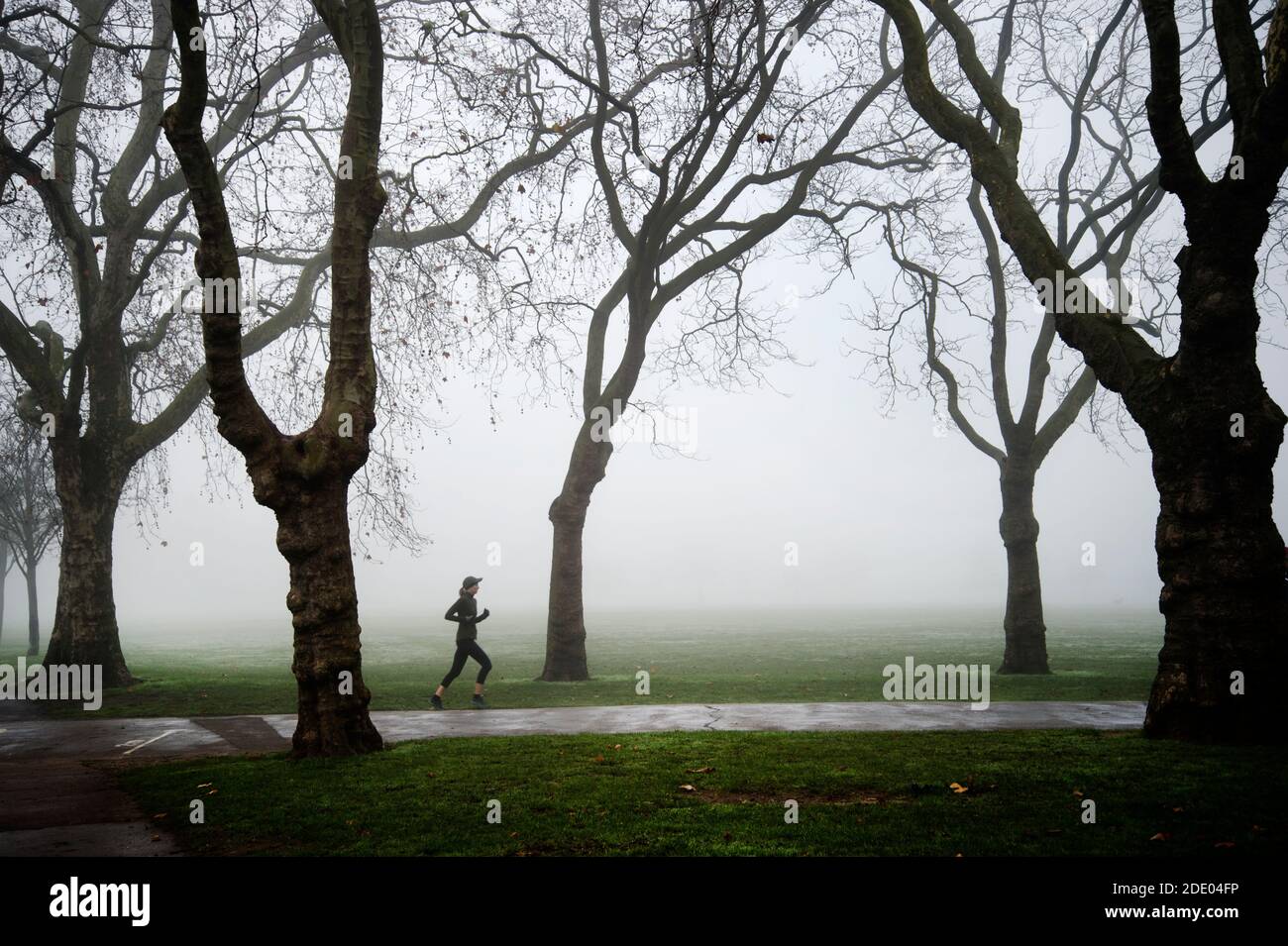Victoria Park, Londres Noviembre de 2020 durante la pandemia de Covid-19 (Coronavirus). Neblina de la mañana. Corredor solitario Foto de stock