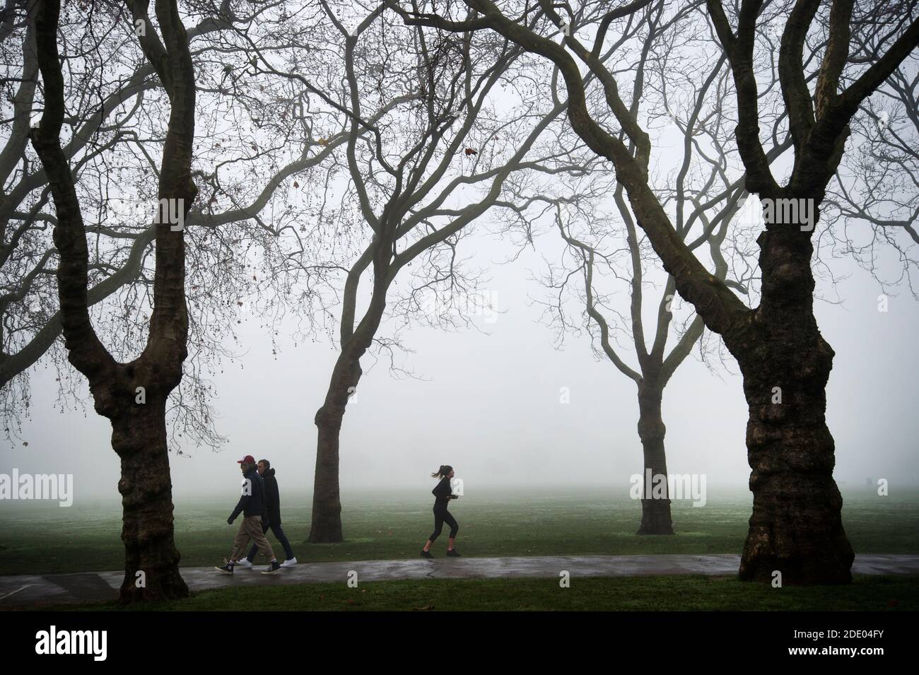Victoria Park, Londres Noviembre de 2020 durante la pandemia de Covid-19 (Coronavirus). Neblina de la mañana. Corredor solitario y caminantes Foto de stock