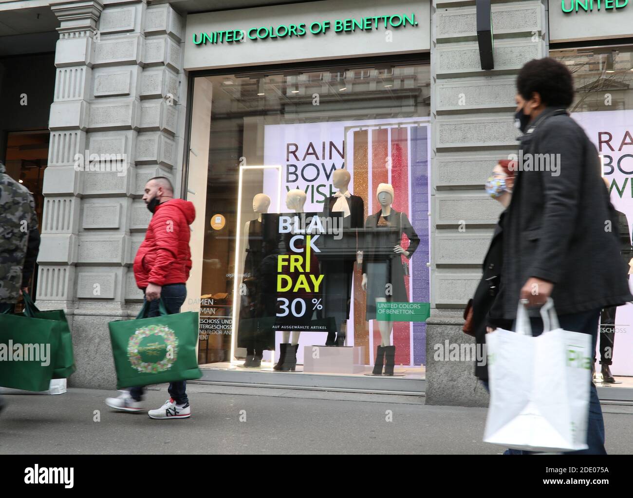 Los compradores pasan por delante de un cartel que ofrece un descuento  especial en las ventas del Black Friday en una tienda de United Colors of  Benetton, ya que la propagación de