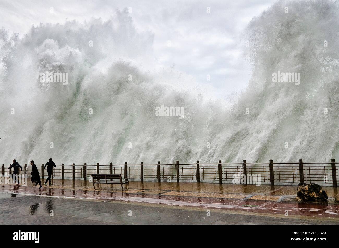 San Sebastián, Guipúzcoa, España; 7 de febrero de 2016; una gran ola cae en el paseo marítimo y en algunos niños Foto de stock