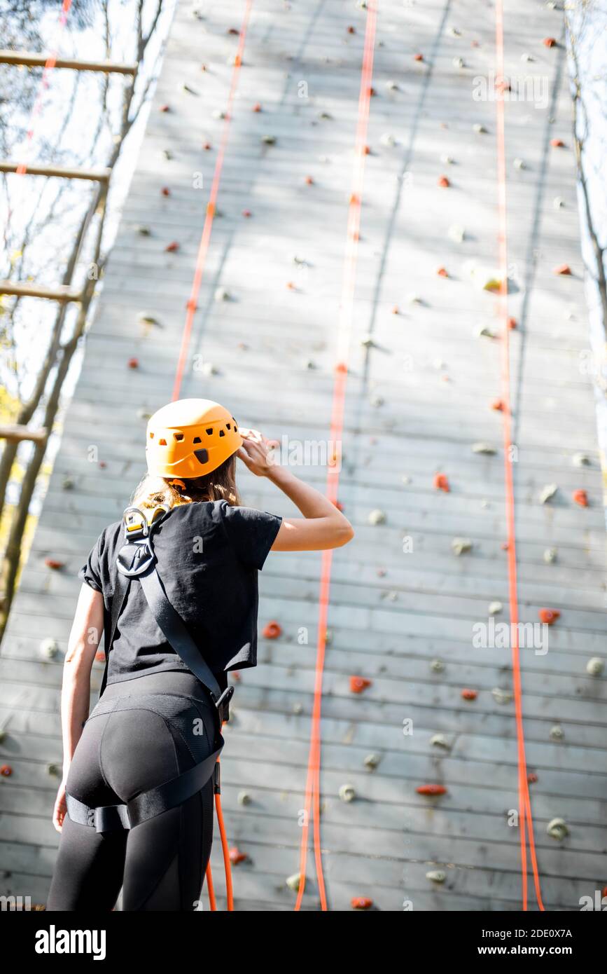 Mujer joven en ropa deportiva y equipo de seguridad mirando en la pared de  escalada antes de escalar. Vista desde la parte trasera Fotografía de stock  - Alamy
