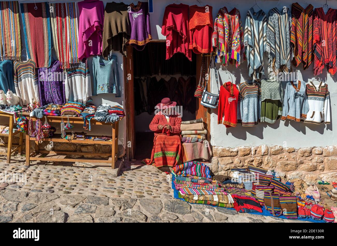 Mujer indígena quechua peruana sentada y tejiendo una tela tradicional  frente a su tienda de artesanía, Chinchero, Perú Fotografía de stock - Alamy