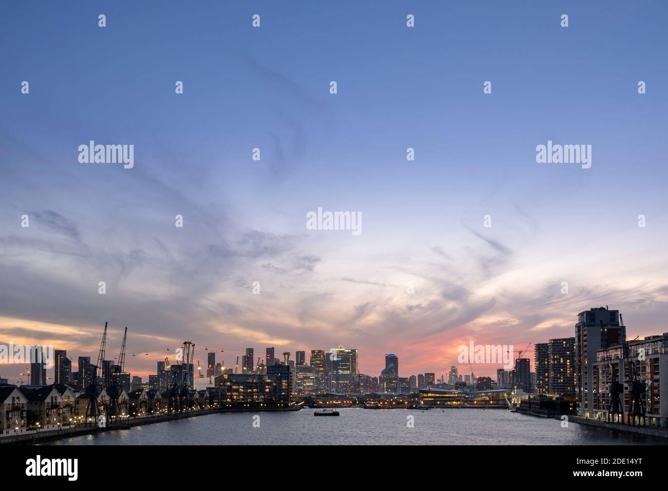 El horizonte de Londres al atardecer con Canary Wharf y los distritos financieros de la Ciudad de Londres, el teleférico Emirates y el muelle Victoria, Londres Foto de stock