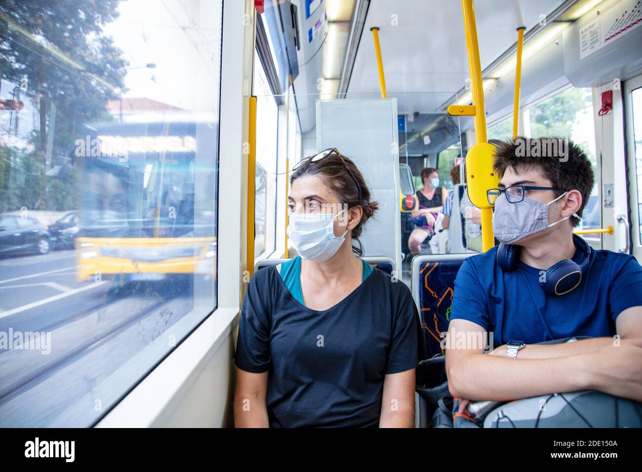 Una madre e hijo que lleva máscaras de protección de la salud en un tranvía público (tranvía), Lisboa, Portugal, Europa Foto de stock