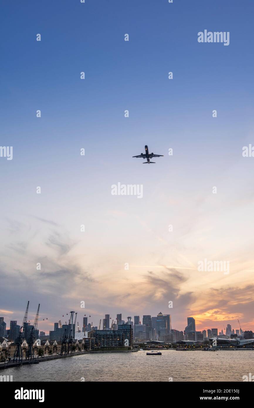 Un avión que llega al aeropuerto de la ciudad de Londres con el muelle Victoria y el horizonte del distrito financiero, Docklands, Londres Foto de stock