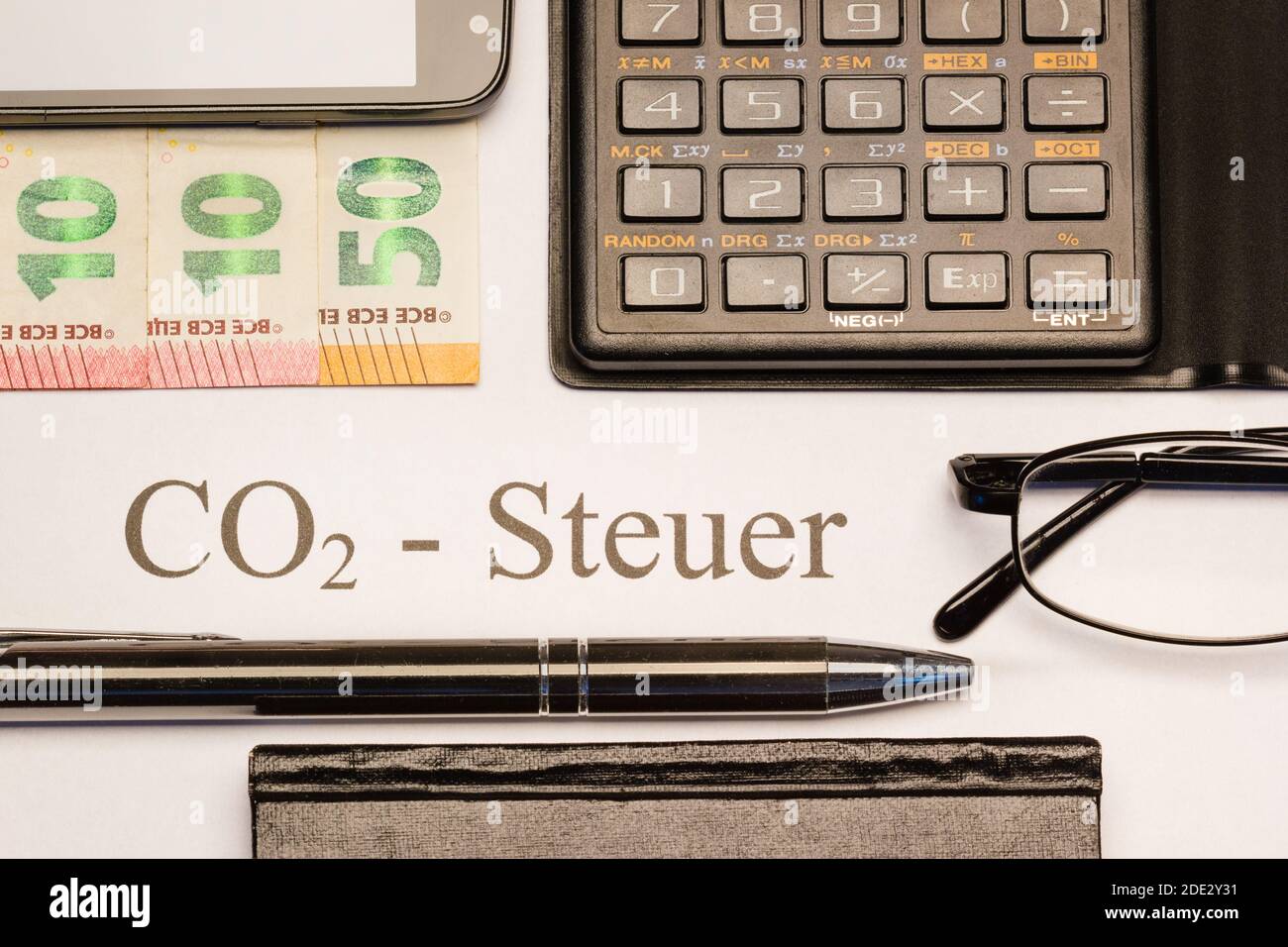 CO2-Steuer gedruckt auf Papier mit Kugelschreiber, Geldscheinen, Taschenrechner, Notizbuch und Handy Foto de stock