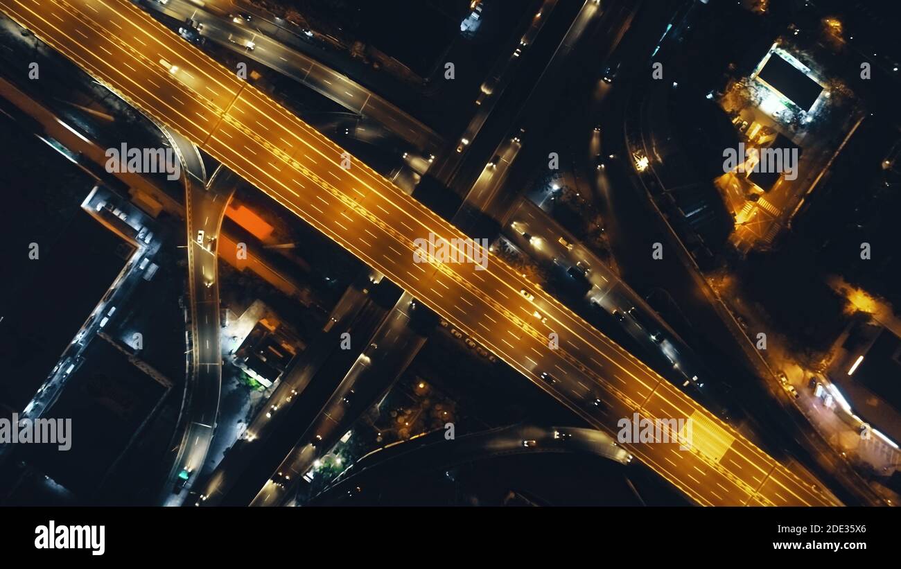 Arriba abajo de la carretera de tráfico con linternas en la noche iluminar la vista aérea. Metrópolis paisaje urbano con modernos edificios de neón resplandecientes en la oscuridad crepúsculo. Película filipina ciudad de Manila en el tiro de drone Foto de stock