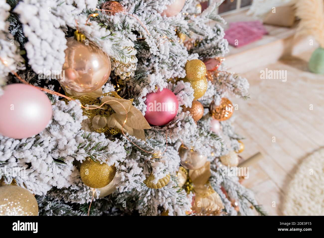 Árbol de Navidad decorado con juguetes de color dorado y rosa. Adornos de  Navidad, cintas, ciervo figura palo, cuentas y luces brillante guirnalda.  Invierno Fotografía de stock - Alamy