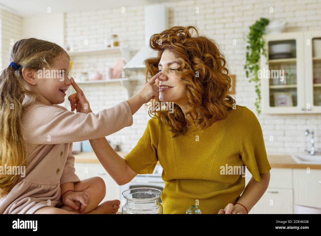La madre y la hija preparan un pastel juntos en la cocina Foto de stock