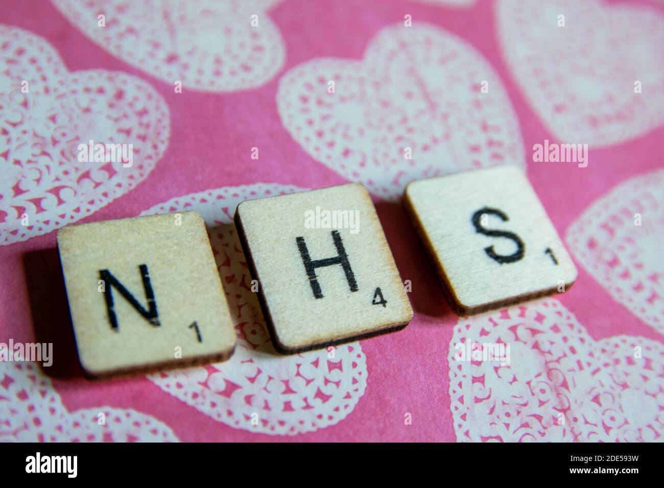 Viejos cubos de madera vieja y envejecer texturizados que deletrean NHS, el Servicio Nacional Británico de la Salud, en un colorido fondo con diseños y espacio para copiar te Foto de stock