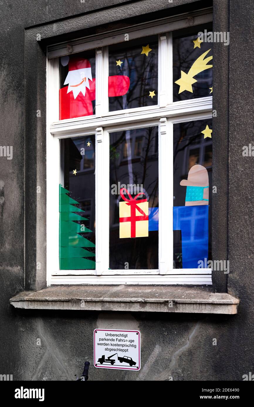 Dortmund, Alemania, 29 de noviembre de 2020: Nikolaus con el logotipo de Amazon como su boca entrega el paquete, el hombre que da lleva la boca y la nariz protección contra el virus. Ventana del apartamento decorada para Navidad indica Nochebuena en Corona Times. Foto de stock
