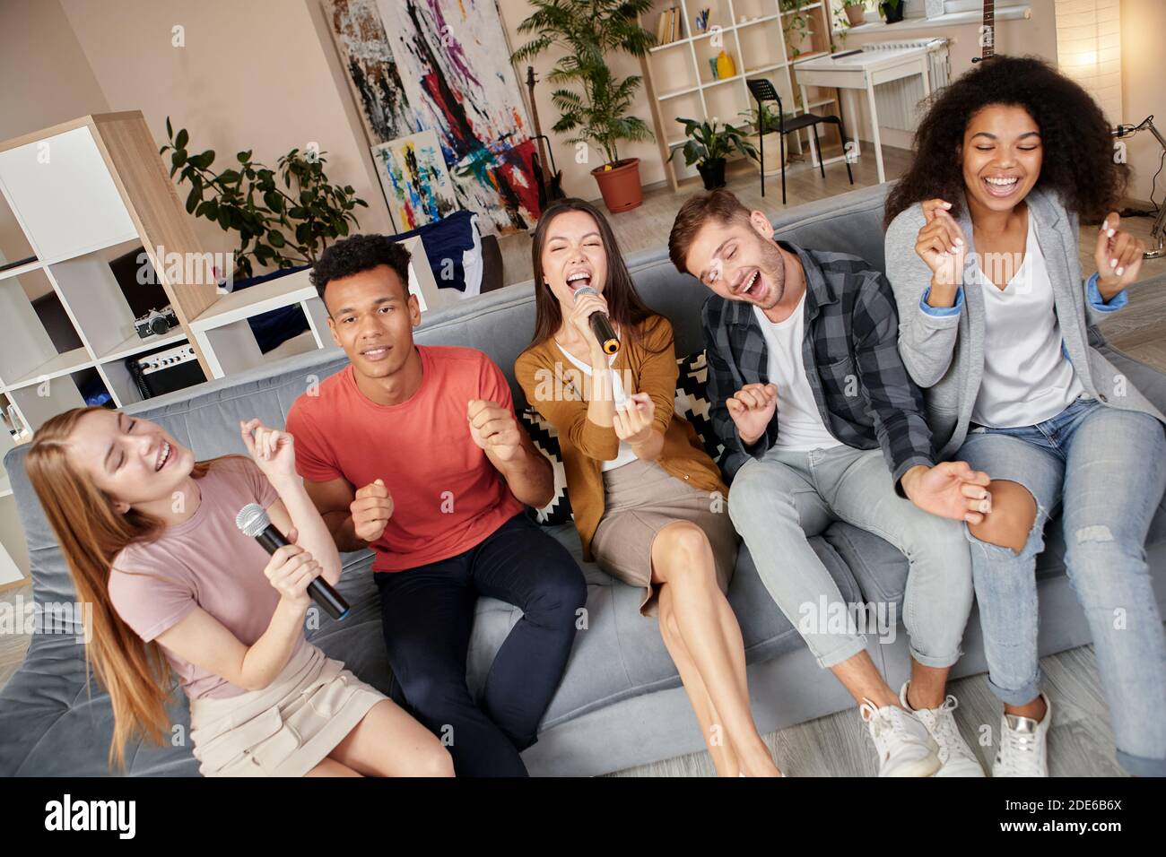 Aficionados al karaoke. Amigos sonriendo mirando emocionados mientras  juegas karaoke en casa, cantando con micrófono, sentados en el sofá en el  apartamento moderno Fotografía de stock - Alamy