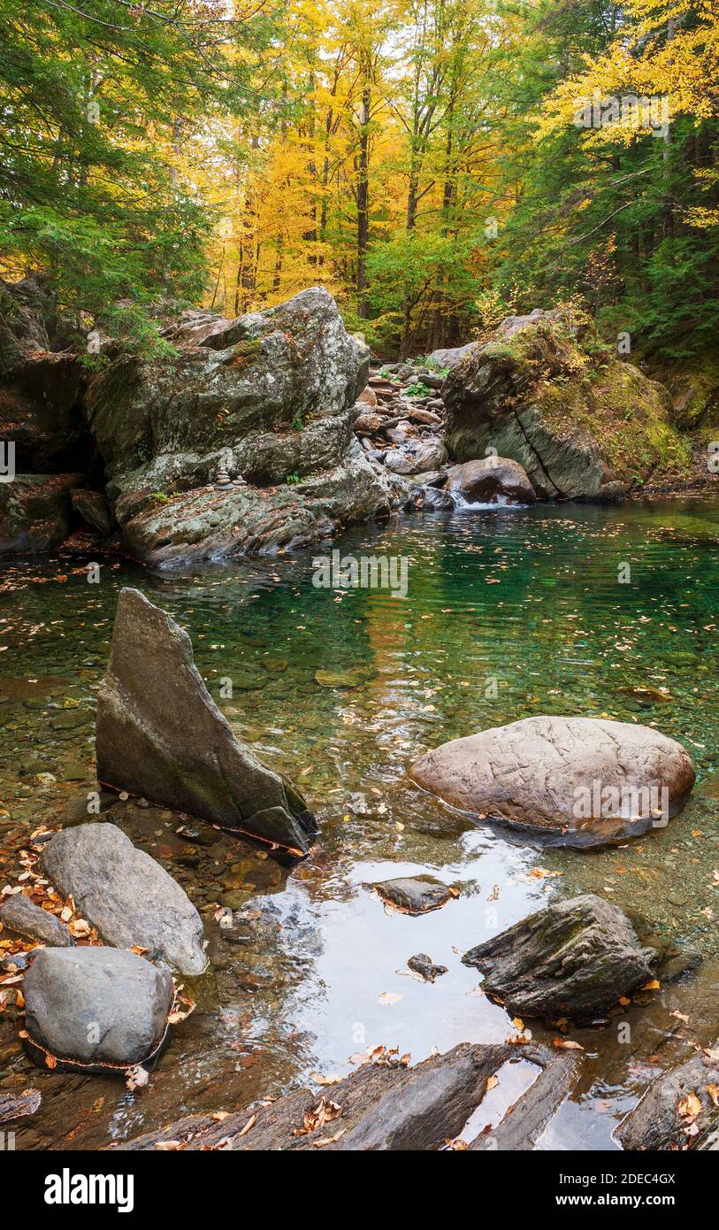 Arroyo en cascada entre grandes rocas en una piscina de agua esmeralda cristalina. Piscina en el río Mad. Los árboles cambian de color en el otoño. Warren, VT, EE.UU Foto de stock