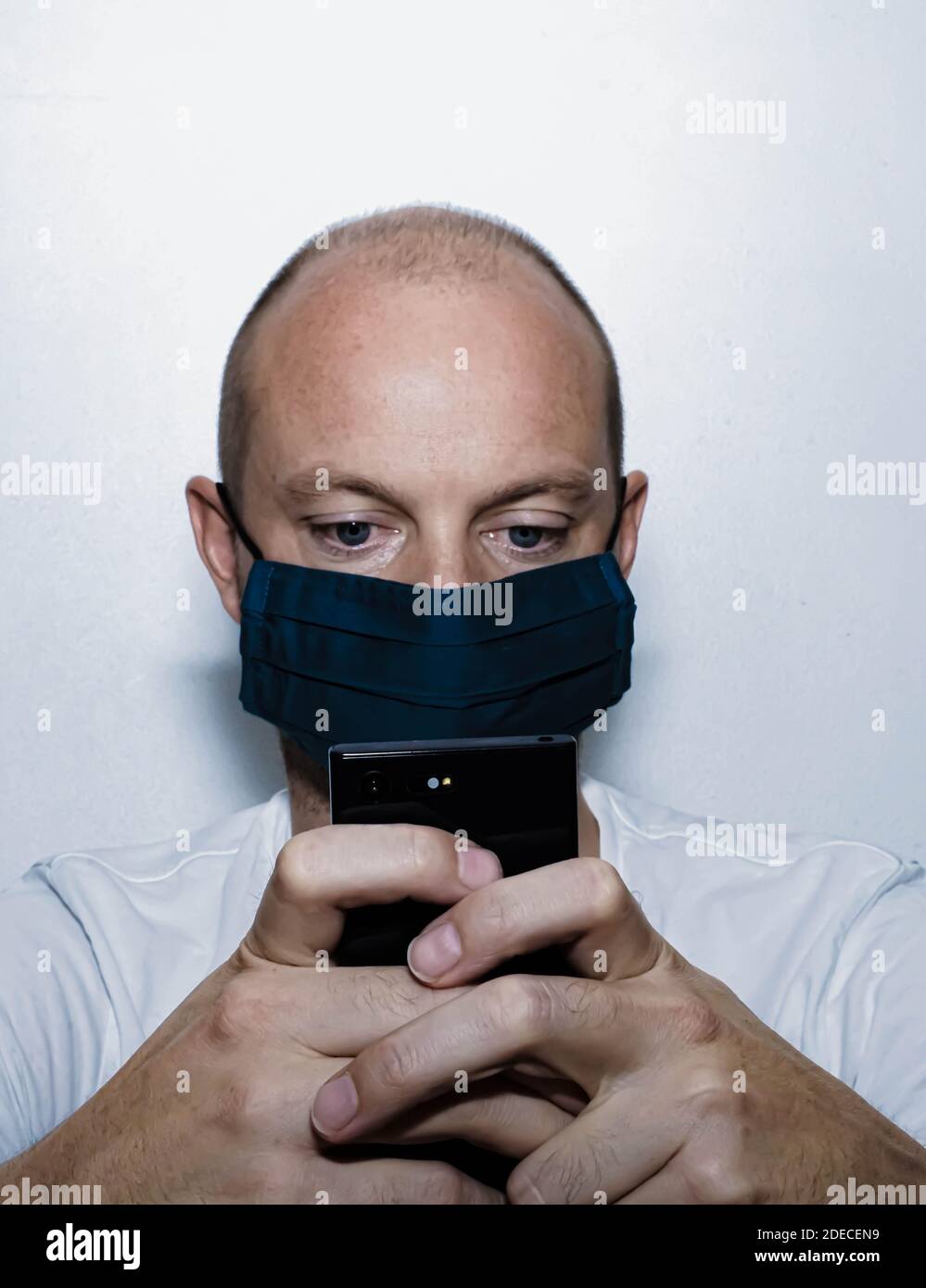 Hombre con máscara para la protección contra virus, leyendo noticias en su  teléfono móvil mientras está aislado. . Foto de alta calidad Fotografía de  stock - Alamy