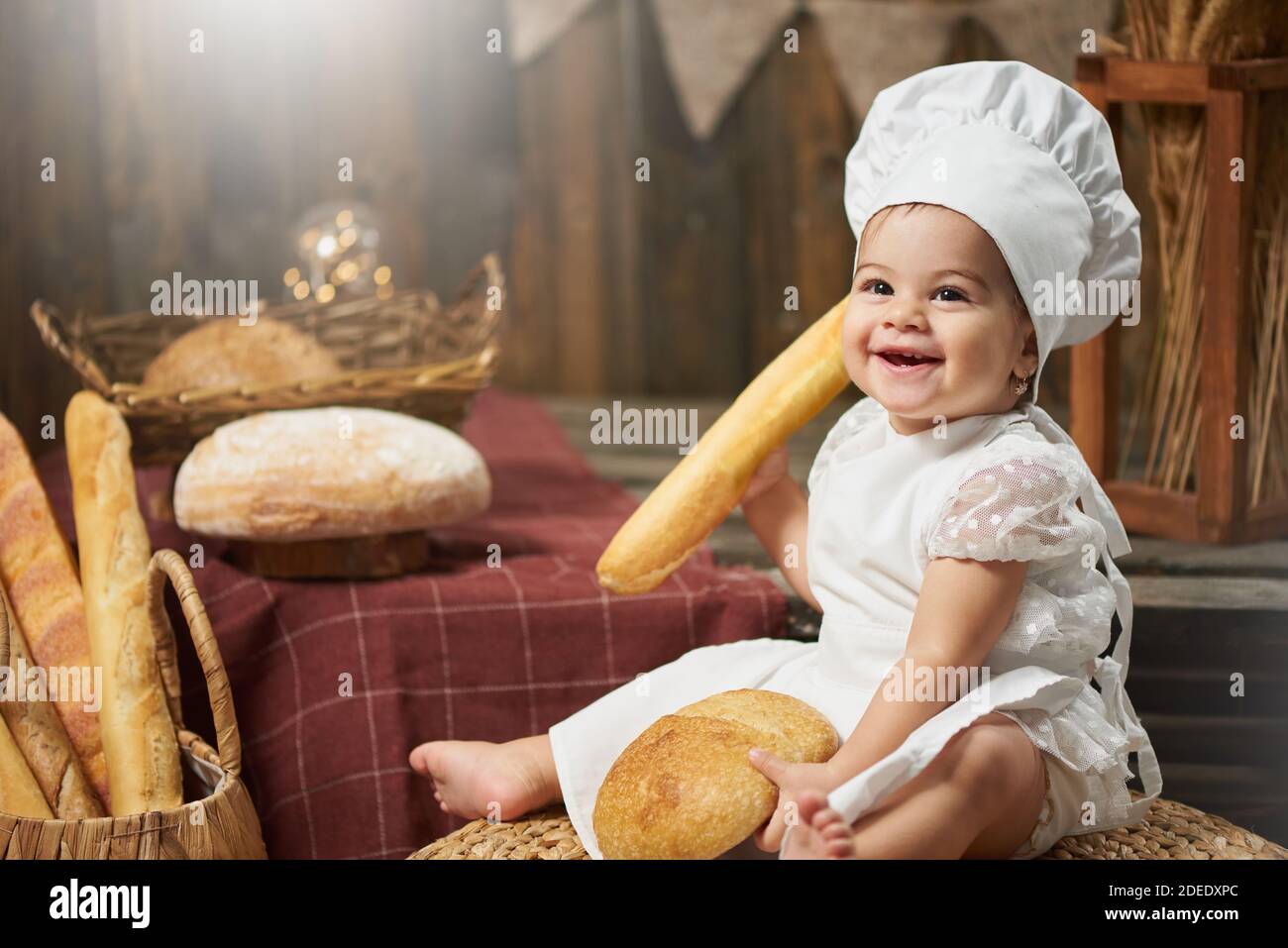 Feliz panadero de bebé sosteniendo pan y sonriendo Foto de stock