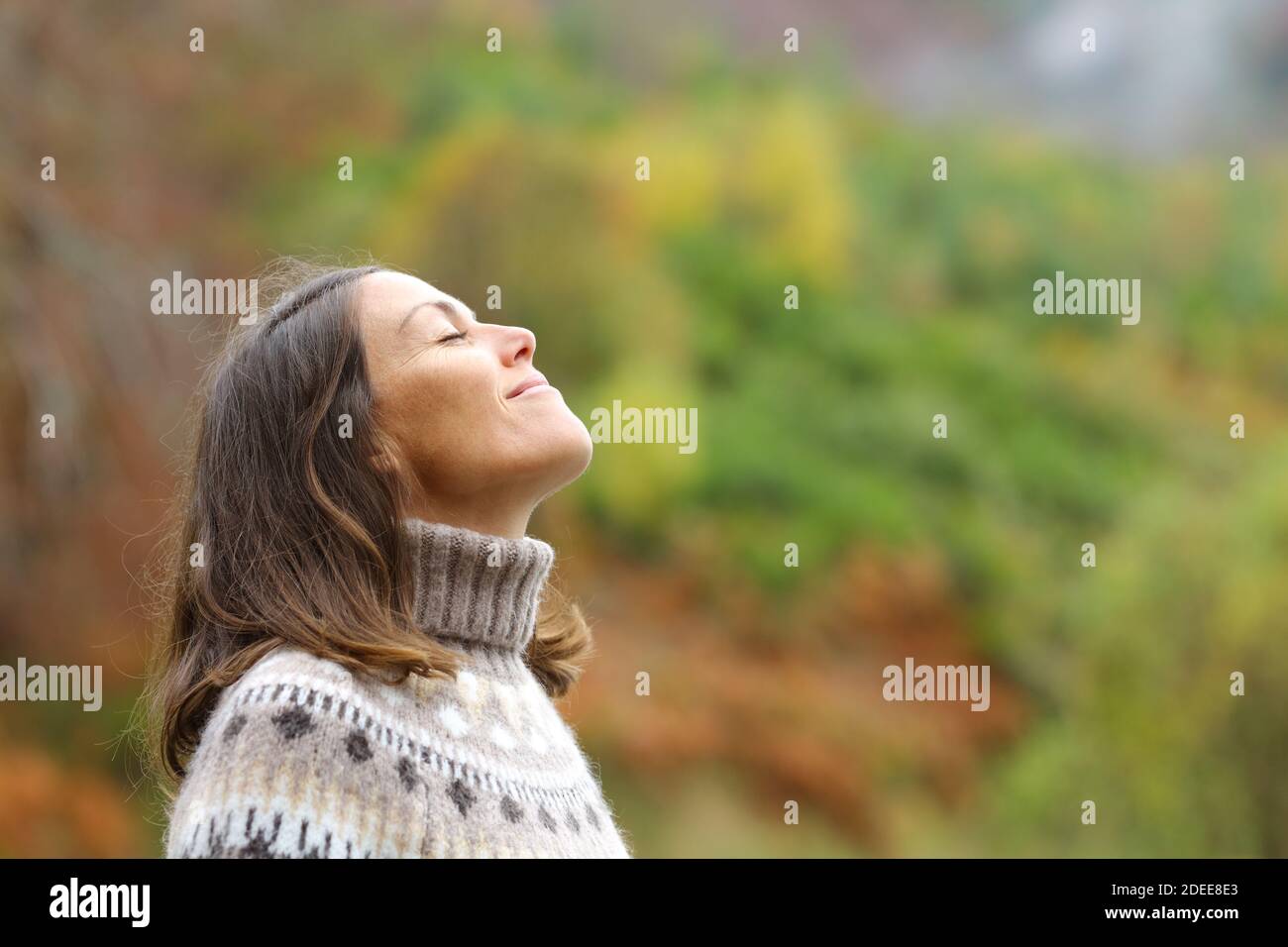 Vista lateral retrato de una mujer de mediana edad respirando fresco aire en un bosque Foto de stock