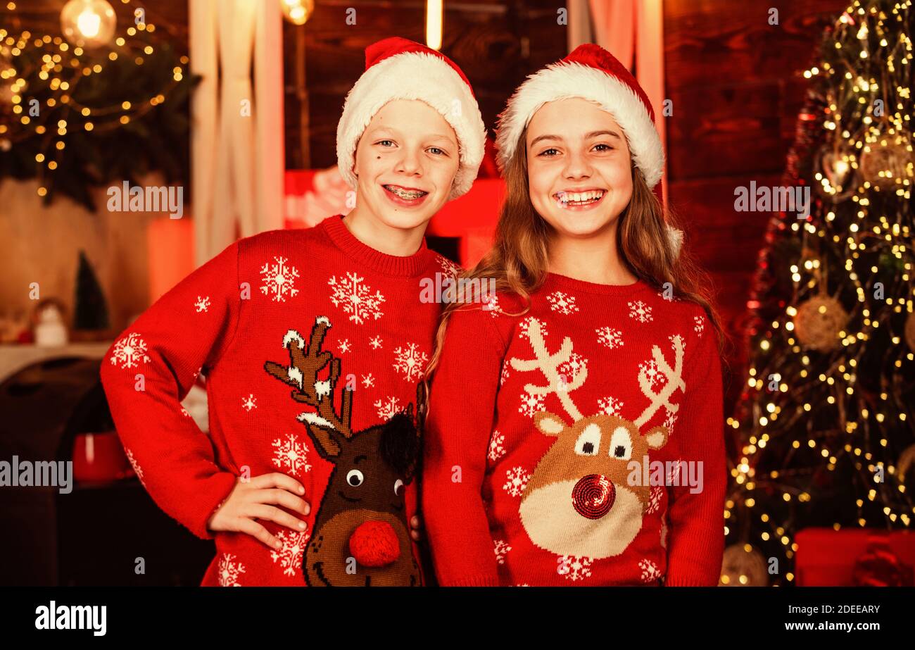 Concepto de convivencia. Ambiente festivo el día de Navidad. Aspecto  familiar. Suéter traje. Chico y chica gorros de Santa Claus. Los niños de  amigos durante las vacaciones de Navidad. Alegría y Noel.