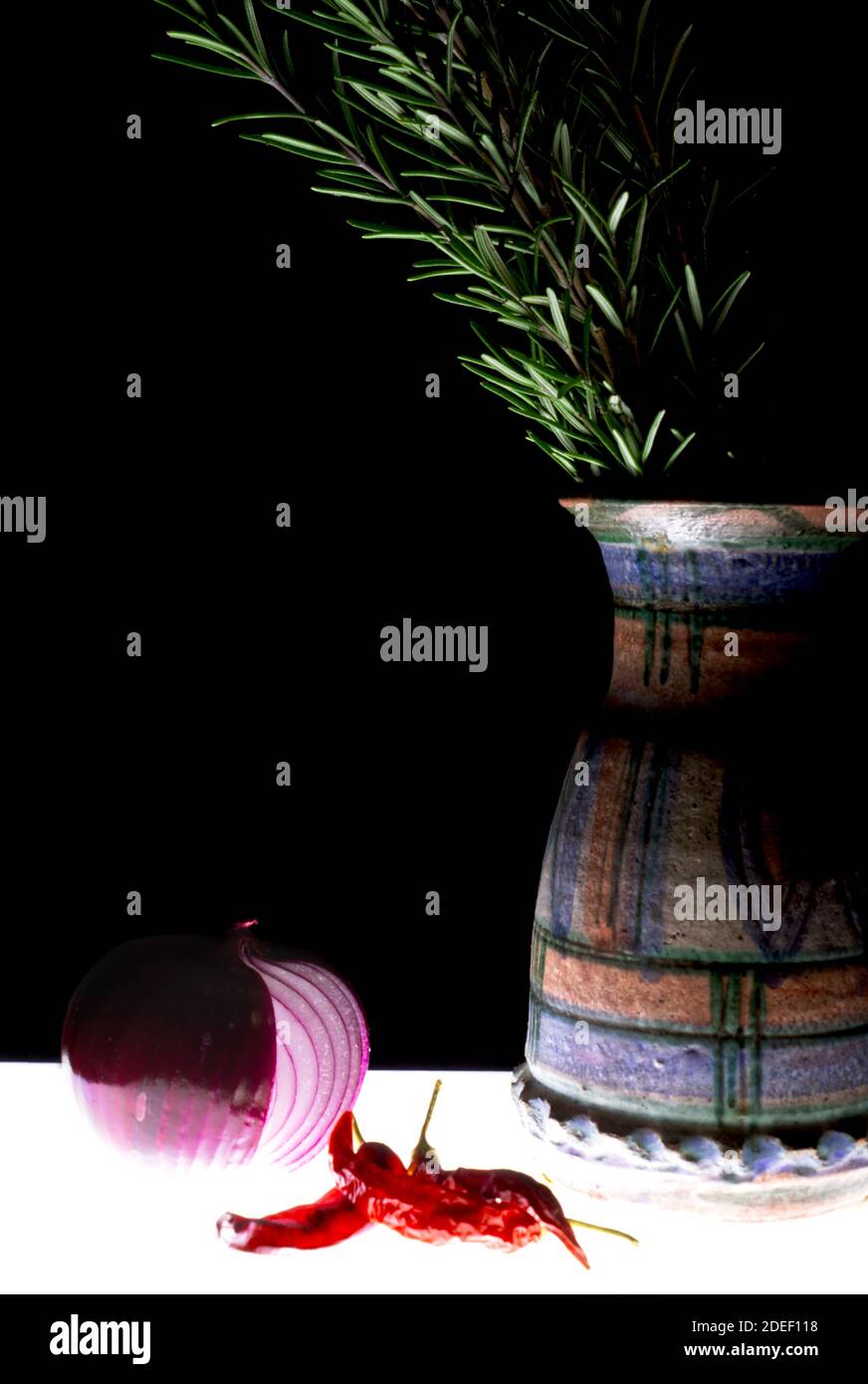 jarrón de terracota decorado a mano con romero de cebolla y chile en un ambiente oscuro Foto de stock