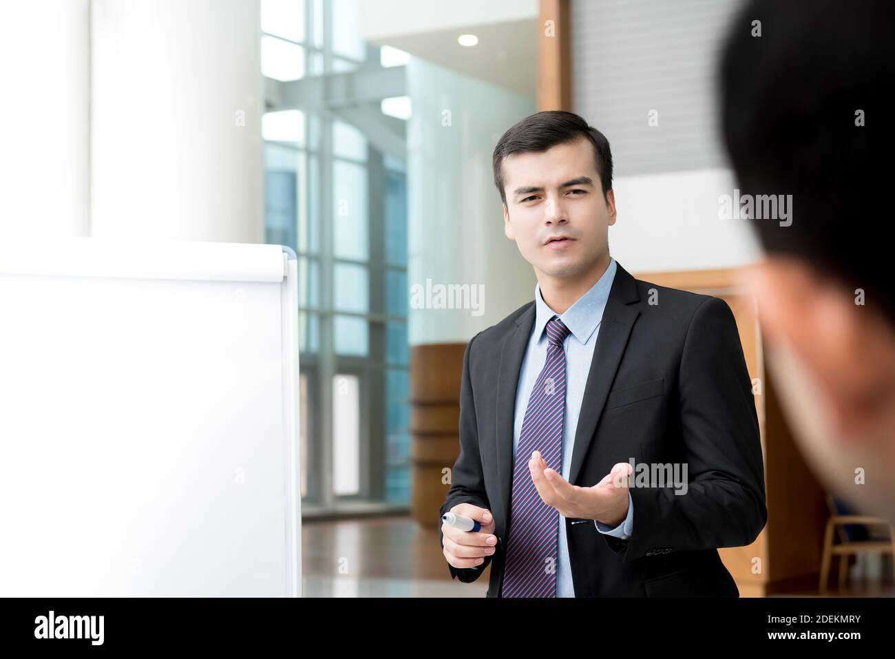 Un hombre de negocios con confianza y guapo presentando un plan de actividades a su colega público en equipo Foto de stock
