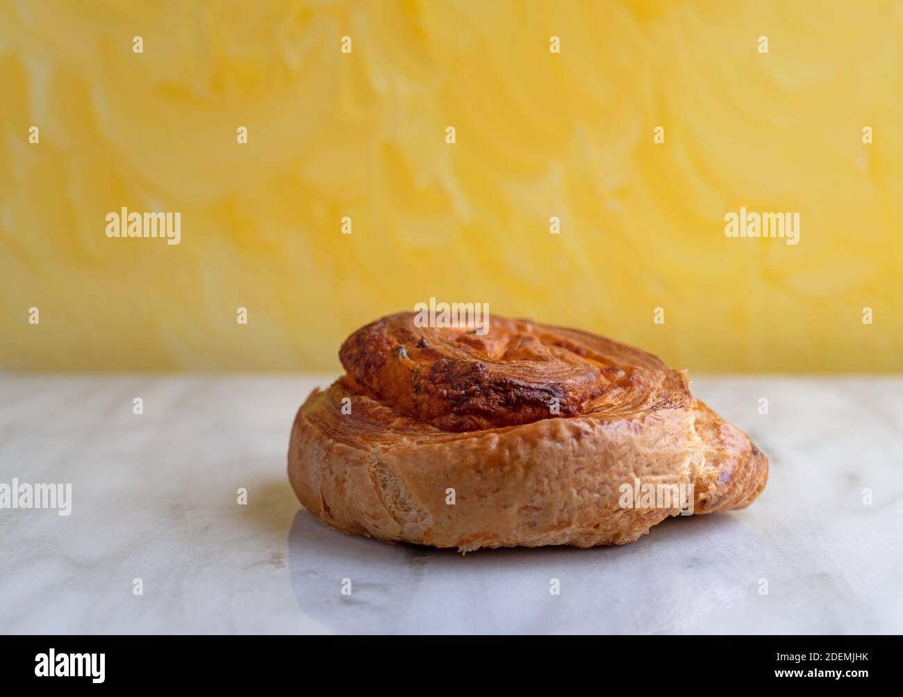 Vista lateral de un solo pan de jalapeno una encimera de mármol gris con una pared con textura amarilla el fondo iluminado con l natural Foto de stock