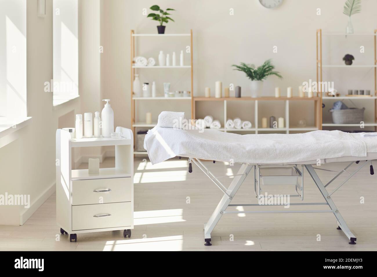 El consultorio del cosmetólogo con cosméticos de cuidado y mesa de masaje en un moderno salón de belleza. Foto de stock