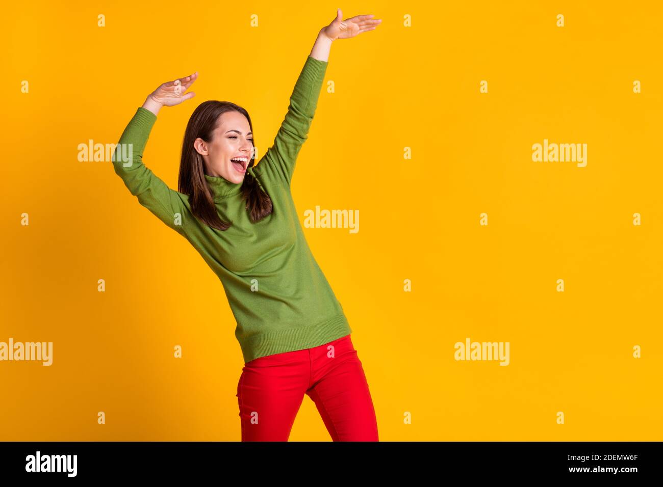 Foto de la chica joven funky baile disco golpe fiesta ropa verde pulóver  pantalón rojo aislado color amarillo fondo Fotografía de stock - Alamy