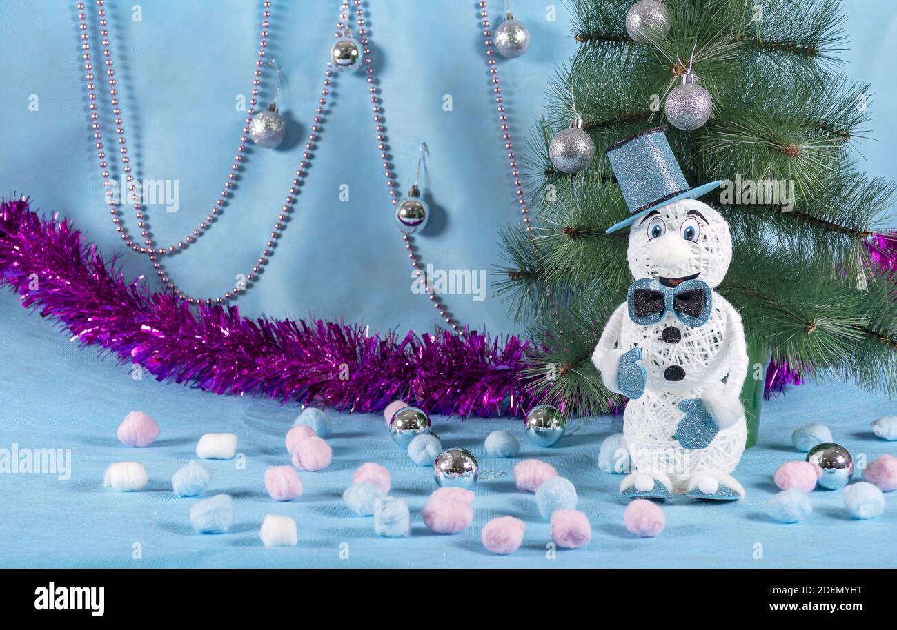 Un muñeco de nieve alegre pero solitario en un traje azul se levanta junto  a un árbol verde en un año nuevo azul escena Fotografía de stock - Alamy