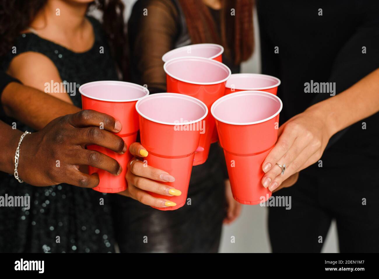 Seis amigos se divierten y beben alcohol durante la fiesta de año Nuevo,  aislados sobre fondo blanco. Un grupo de amigos alegres de diferentes  nacionalidades se aferran a las gafas rojas en