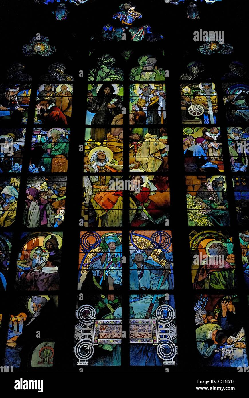 Vívido cristal Art Nouveau de la década de 1930 de Alphonse Mucha en una ventana de la Capilla del Nuevo Arzobispo en la Catedral de San Vito en Hradčany, Praga, capital de la República Checa / República Checa. La ventana, una alegoría de Cristo bendiciendo a las naciones eslavas, incluye al patrón checo san Wenceslao, duque de Bohemia, representado como un niño rezando con su abuela, Santa Ludmila, escenas de la vida de los misioneros apóstoles a los santos eslavos Cirilo y Metodio, Y también una figura femenina de ‘Shavia’ por encima de un tributo escrito al banco que financió las obras de arte de Mucha. Foto de stock