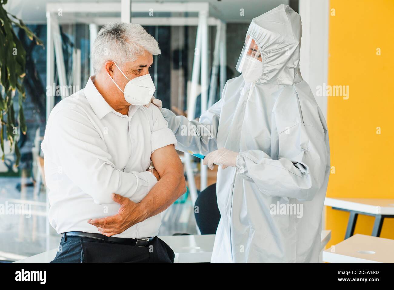 anciano latino recibiendo la vacuna para un médico mexicano Mujer con mascarilla para la pandemia de coronavirus en la ciudad de México Foto de stock
