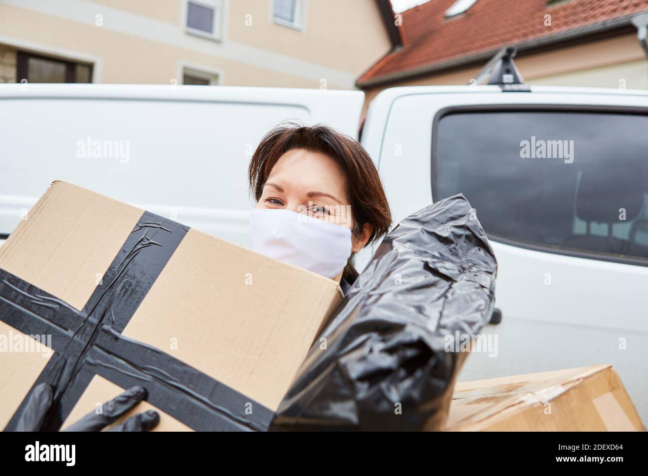 Servicio de entrega de transporte de paquetes con máscara exterior realiza muchos paquetes para la entrega Foto de stock