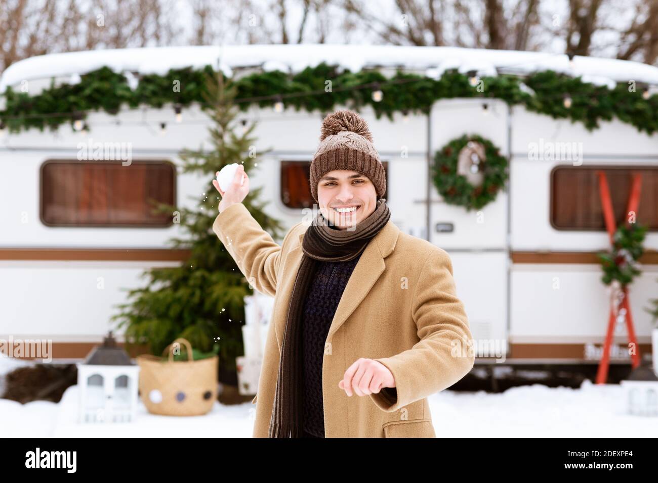Diversión de invierno. Hombre Milenario alegre apuntando bola de nieve a la Cámara, lanzando nieve Foto de stock