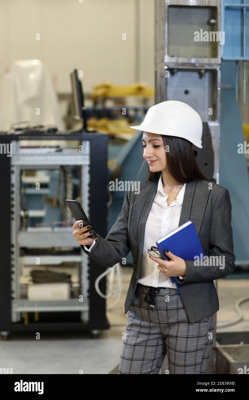 Retrato de una mujer gerente de fábrica en un traje de negocios portatil, controlando el proceso de trabajo en el fabricante. . Foto de alta calidad Foto de stock