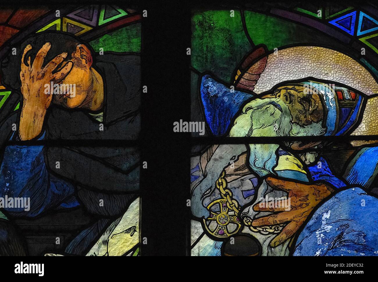 El luto penoso cubre los ojos mientras coloca el reconfortante brazo alrededor de los hombros del agonizante teólogo bizantino y misionero San Metodio (815-885 DC), en vívido 1930 vidrieras del influyente artista Art Nouveau Alphonse Mucha en la capilla del nuevo arzobispo de la catedral de San Vito en Praga, capital de la República Checa. La ventana completa, una alegoría de Cristo que bendice a las naciones eslavas, presenta escenas de la vida de los ‘Apóstoles a los eslavos’ Metodio y su hermano Cirilo, así como el patrón checo san Wenceslao, Duque de Bohemia, y su abuela, San Ludmila. Foto de stock