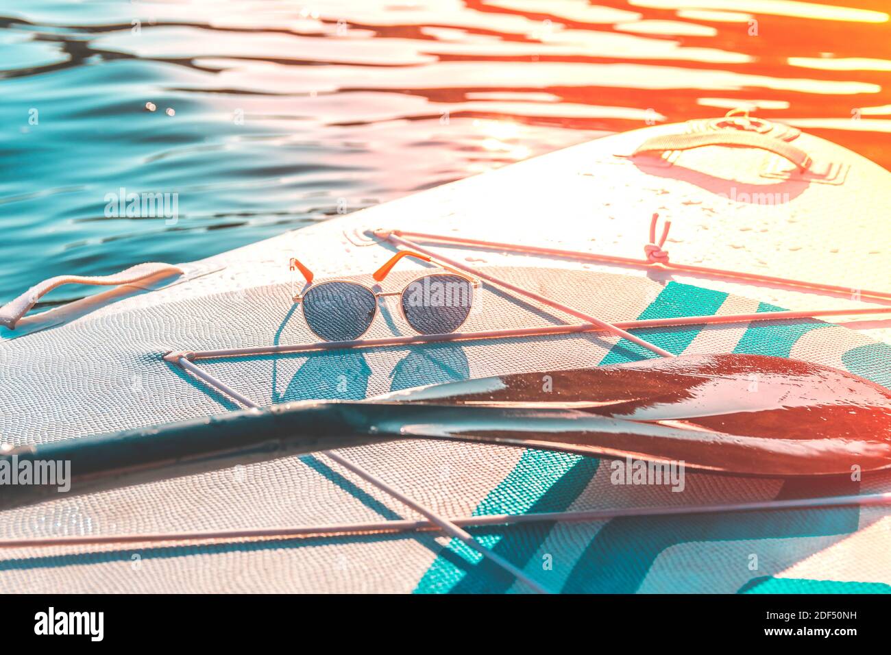 Gafas de sol de moda en un surf de remo. Relájese y viaje. Día caluroso de verano. Deportes acuáticos. Vacaciones en el mar. Foto de stock