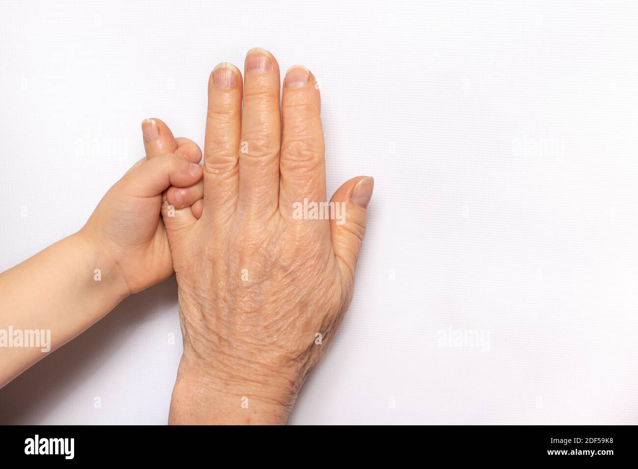 Las manos de los niños pequeños en manos de una abuela mayor. La vejez y la infancia, la comunicación de la abuela con el nieto, el envejecimiento, la edad y la vida Foto de stock