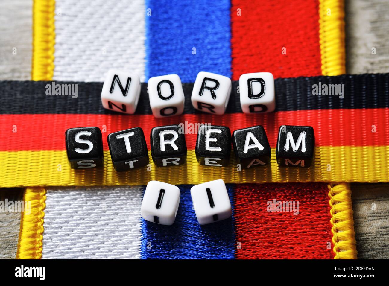 Letra cubos que forman las palabras Nord Stream 2 en el Banderas de Rusia y Alemania Foto de stock