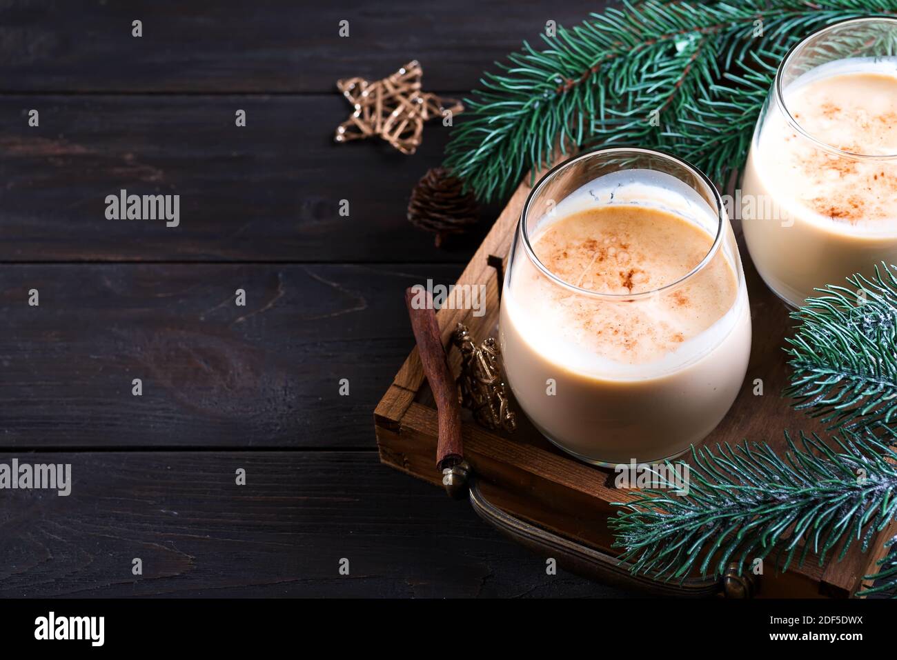 Cóctel de leche de Navidad con canela, servido en dos vasos en vintage con rama de abeto fondo de madera oscura de stock - Alamy