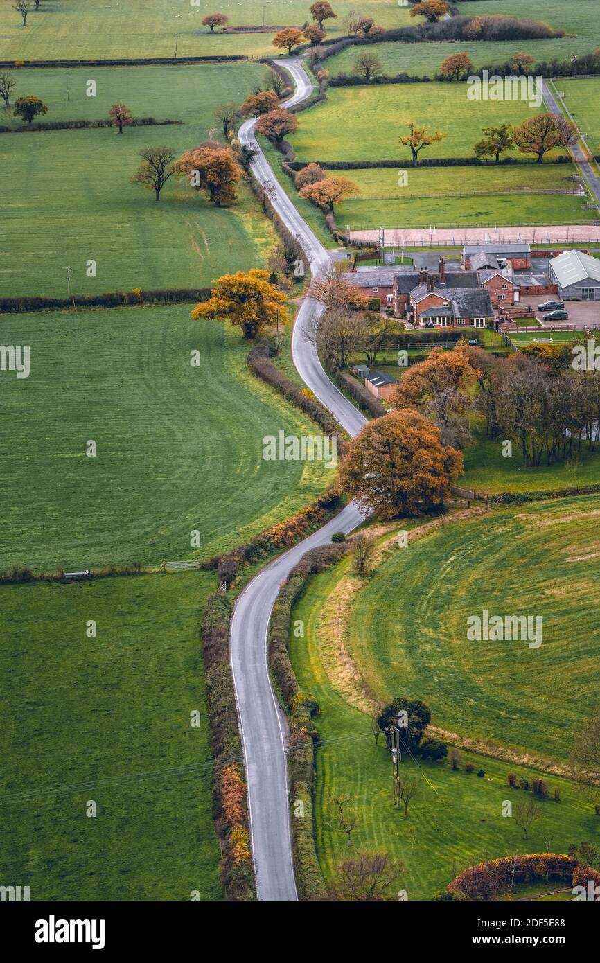 Imagen vertical largo camino ventoso cortando a través de English campo en Cheshire. Baleado aéreo durante un día frío en noviembre Foto de stock
