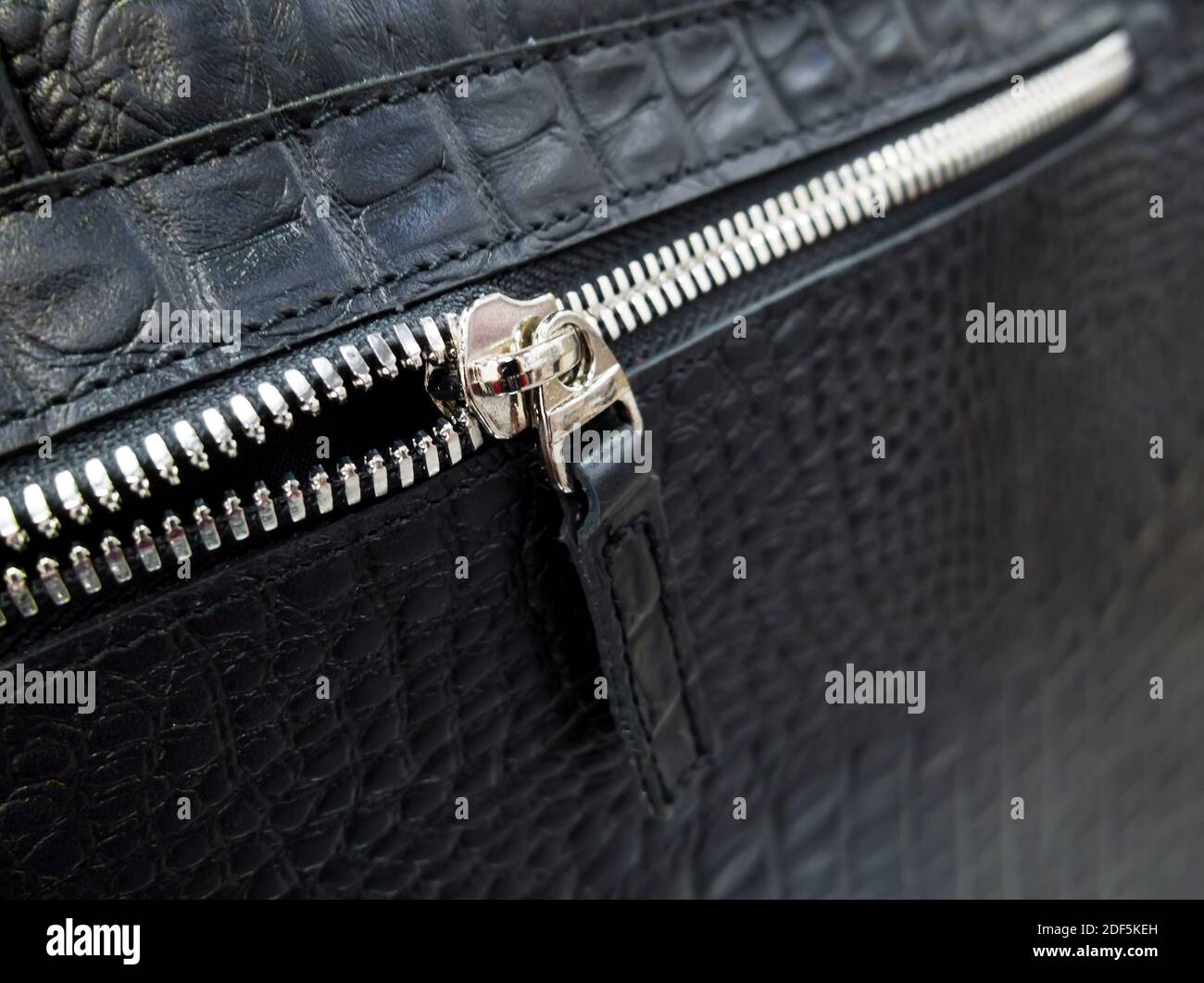 Cierre de cremallera en tono plateado en una bolsa de cuero negro Foto de stock