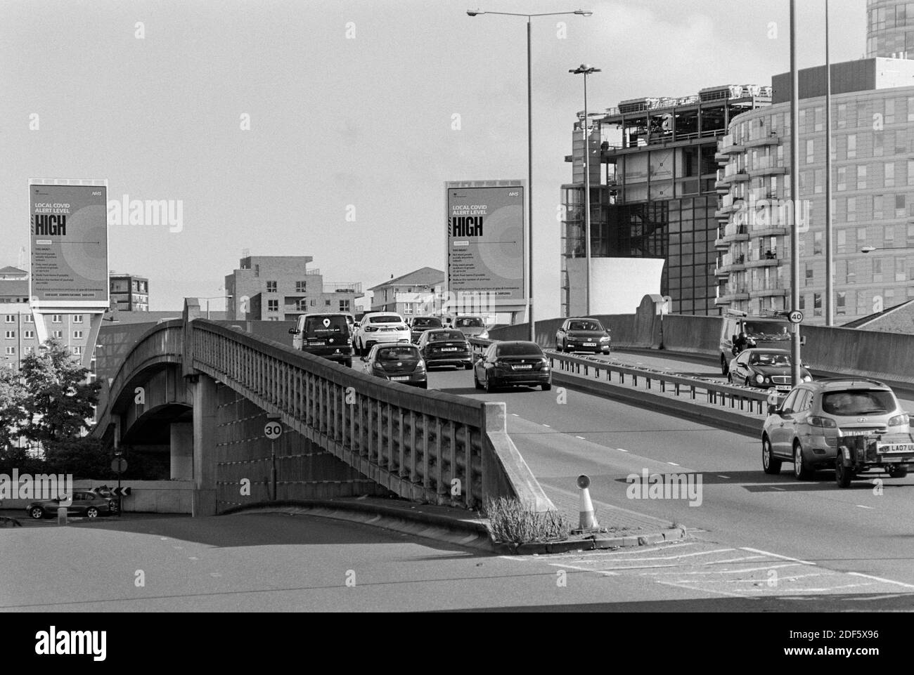 Tráfico en Aspen Way cerca de Canary Wharf, London Docklands, Reino Unido, con pantallas electrónicas que avisan a los conductores de la alerta alta de nivel 2 de Londres para Covid 19 Foto de stock