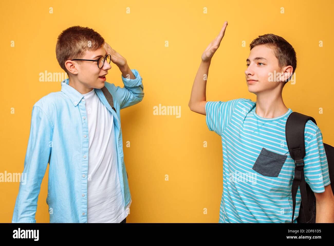 Dos adolescentes con estilo, chicos se saludan unos a otros, sobre un fondo amarillo Foto de stock